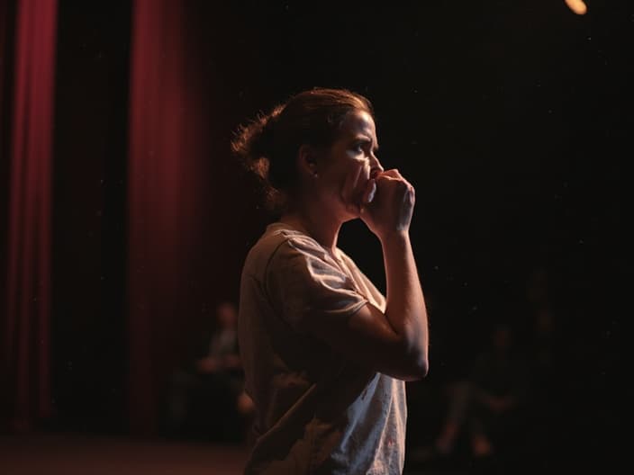 Person taking deep breaths before entering a stage, looking nervous but determined